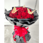 Bouquet of red roses wrapped in black paper with a pink ribbon