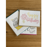 Three birthday greeting cards stacked on a wooden surface