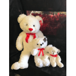 Three white teddy bears with red bows on a dark background