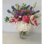 Mixed bouquet of pink roses, lilies, and white hydrangea in a glass vase