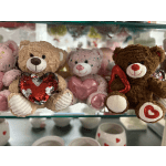 Three teddy bears holding heart-shaped gifts on a shelf