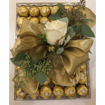 Gift box with a white rose, gold ribbon, and chocolates