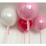 Four pink and white balloons with long ribbons against a plain wall.