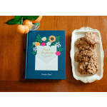 Book beside a plate of cookies and a small vase of oranges