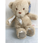 Beige teddy bear with a white ribbon and "my first bear" on its foot