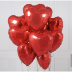 Cluster of red heart-shaped balloons against a white wall