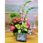 Mixed floral arrangement in a square glass vase with pink and green blooms