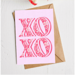 Pink greeting card with floral XO lettering on a kraft envelope