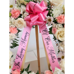 Pink memorial ribbon with large bow on a standing floral wreath for mother