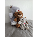 Three plush teddy bears sitting together on a gray surface