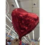 Red heart-shaped foil balloon held indoors