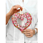 Heart-shaped floral ornament with pink and white blossoms held by a person