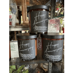 Three anniversary candles in dark glass jars with black lids