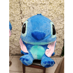 Large blue Stitch plush toy in front of a white flower wall