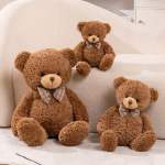 Set of three brown teddy bears with plaid bow ties arranged on a cream sofa.