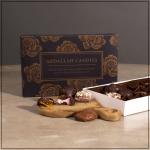 Box of assorted chocolates with a few pieces on a wooden board