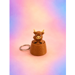 Small bull figurine keychain on a pastel gradient background