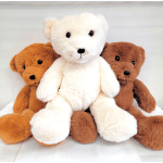 Three plush teddy bears in white, tan, and brown sitting together