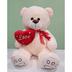 Plush teddy bear holding a red heart pillow