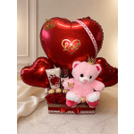 Heart-shaped red balloon gift set with a pink teddy bear, roses, and chocolates