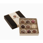 Box of assorted chocolate truffles in an open gold-lined tray beside its black and cream lid