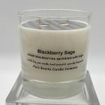 White Blackberry Sage scented candle in a clear glass jar on a glass stand