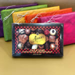 Assorted chocolate gift box with colorful wrapped packages behind it