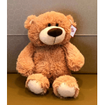 Plush teddy bear with a price tag sitting against a patterned wall