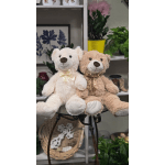 Two teddy bears with satin bows sit on a small table.