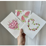 Hand holding three floral watercolor cards with pink designs