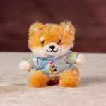 Small plush fox wearing a pastel shirt, seated on a surface