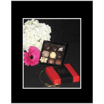 White hydrangeas with a pink gerbera daisy beside a box of chocolates