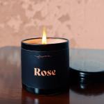 Lit black candle in a round container labeled Rose