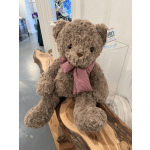 Brown teddy bear with a red gingham bow sitting on a wooden display