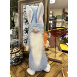 A plush Easter bunny figurine holding a carrot on a wooden table