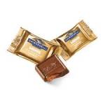 Individually wrapped gold chocolates with one unwrapped chocolate square in front