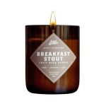 Brown glass jar candle labeled Breakfast Stout craft beer candle with a visible flame.