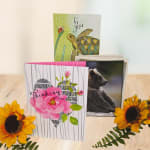 Assorted greeting cards with floral and animal designs on a wooden surface