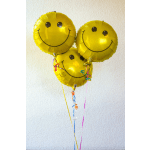 Cluster of three yellow smiley face foil balloons with colorful ribbons.