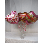 Three heart-shaped Valentine balloons in a glass vase