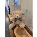 Plush teddy bear with a plaid bow sitting on a wooden bench