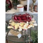 Red roses in a clear plastic box with cream petals around it