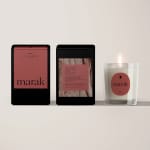 Three marak scented candles in black packaging and a lit glass candle