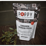 A bag of Poppy cinnamon bourbon pecan popcorn beside a small greenery sprig.