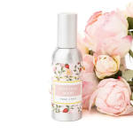 Bottle of botanical berry room spray beside pale pink peonies