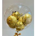 Clear balloon filled with gold balloons and "Happy Birthday" lettering