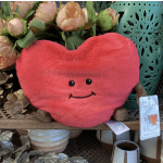 Heart-shaped plush toy in front of peach flowers and a teal lantern