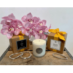 Pink orchids arranged with two boxed candles and a glass candle on a wooden tray