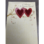 Valentine card with two red glitter hearts and decorative swirls