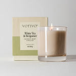 Lit candle in a glass jar beside its box